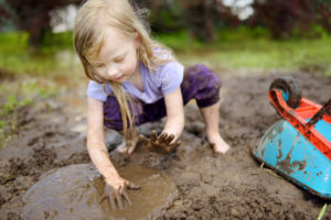 outdoor photograph of girl playing in mud